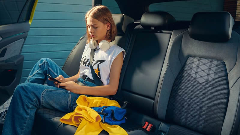 Volkswagen Golf 8 Variant - dívka sedící vzadu ve vozu a hraje hry na mobilu